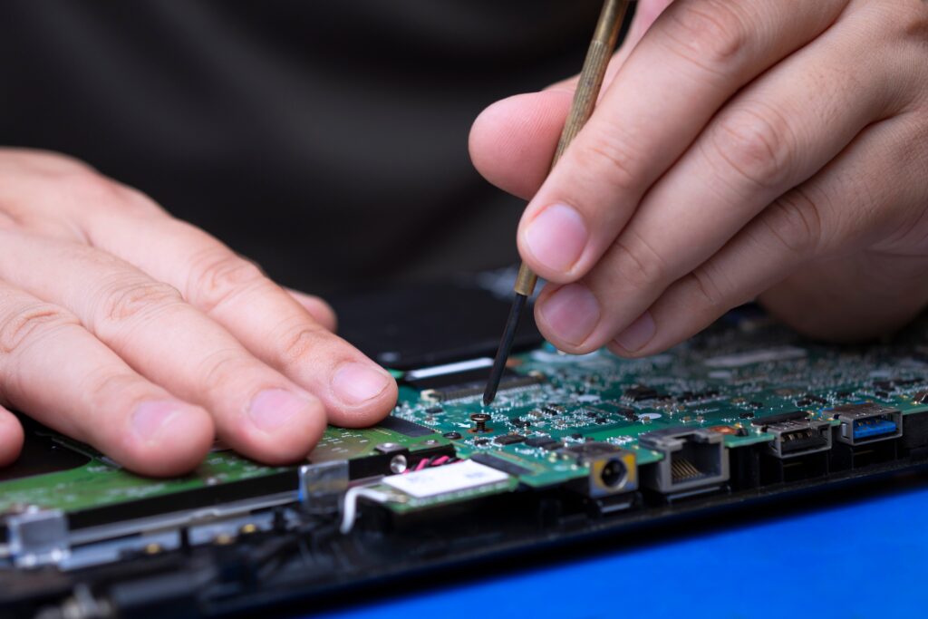 Focus at screw on green mainboard while technician fixing laptop computer